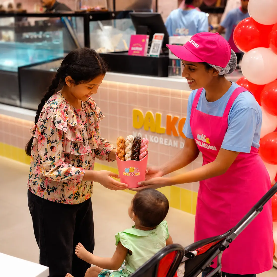 Dalkomi crew handing a bucket of twisted donuts to a young customer