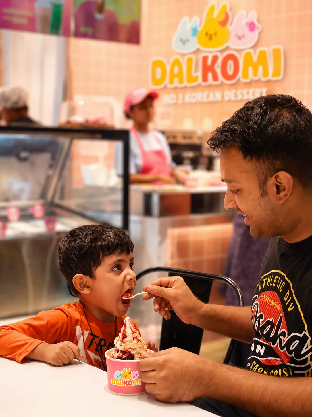 Dad feeding his son a spoonful of Dalkomi sundae