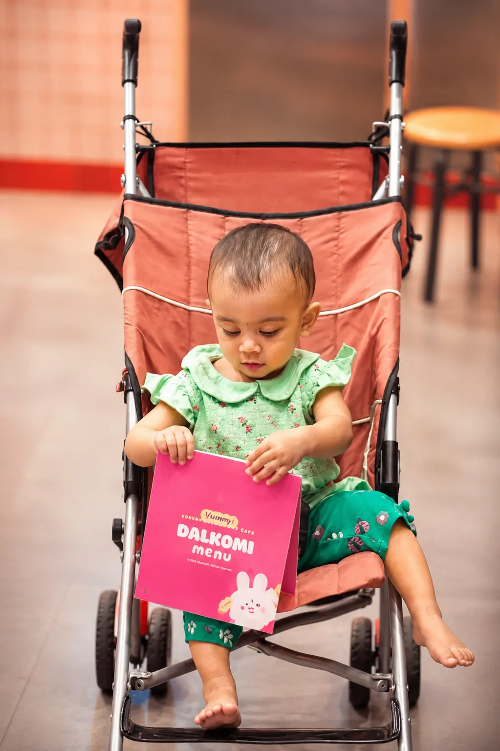 Baby in a stroller holding the Dalkomi menu